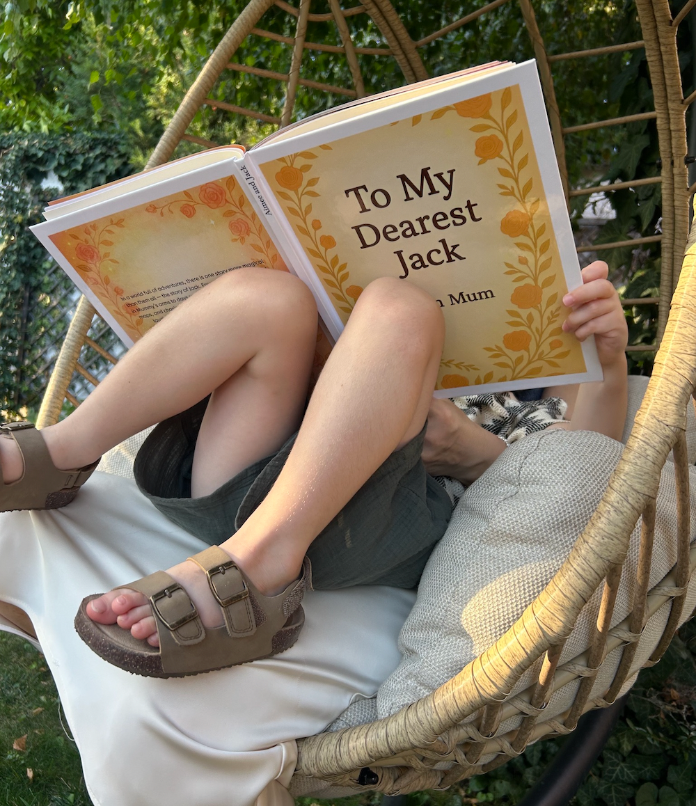 Mum reading a book to his Son titled 'To My Dearest Jack' in a wicker chair outdoors.